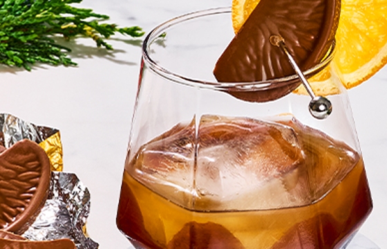 Two chocolate old fashions in geometrical glasses , garnished with a fresh orange slice and Terry’s chocolate orange.